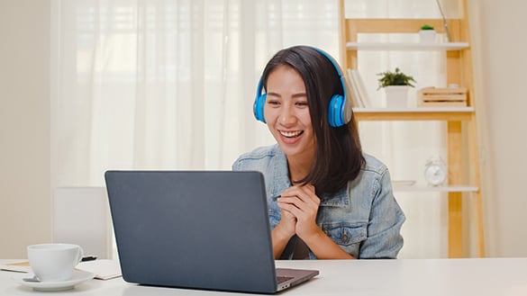 Woman sitting at a laptop computer wearing blue headphones