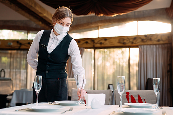 Waitress wearing mask setting table in a restaurant